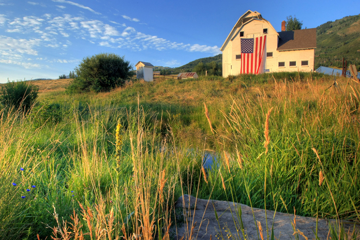 A  white barn with a huge American flag. 