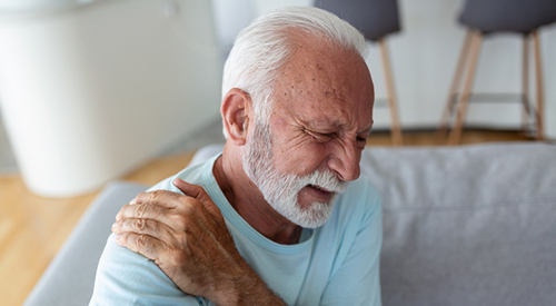  Senior elderly man touching his shoulder, suffering from shoulder pain, sciatica, sedentary lifestyle concept. shoulder health problems.   