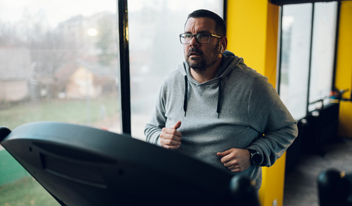 Middle aged man running on a treadmill in the gym 